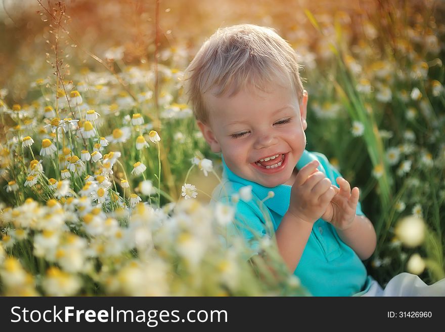 On the nature of the little baby playing and smiling on a field strewn with wild daisies. On the nature of the little baby playing and smiling on a field strewn with wild daisies