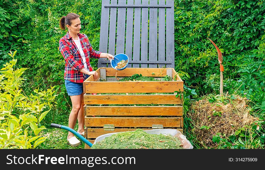 Wooden Compost Bin Close Up. A Gardener Throws Lawn Clippings And Kitchen Waste Into A DIY Compost Bin To Improve The Fertility An
