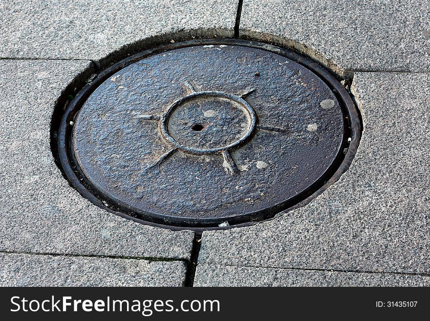 Sewer manhole cover on a granite covering. Sewer manhole cover on a granite covering