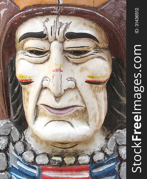Close-up of an old wooden carved and painted face of a North American Indian man. Close-up of an old wooden carved and painted face of a North American Indian man.