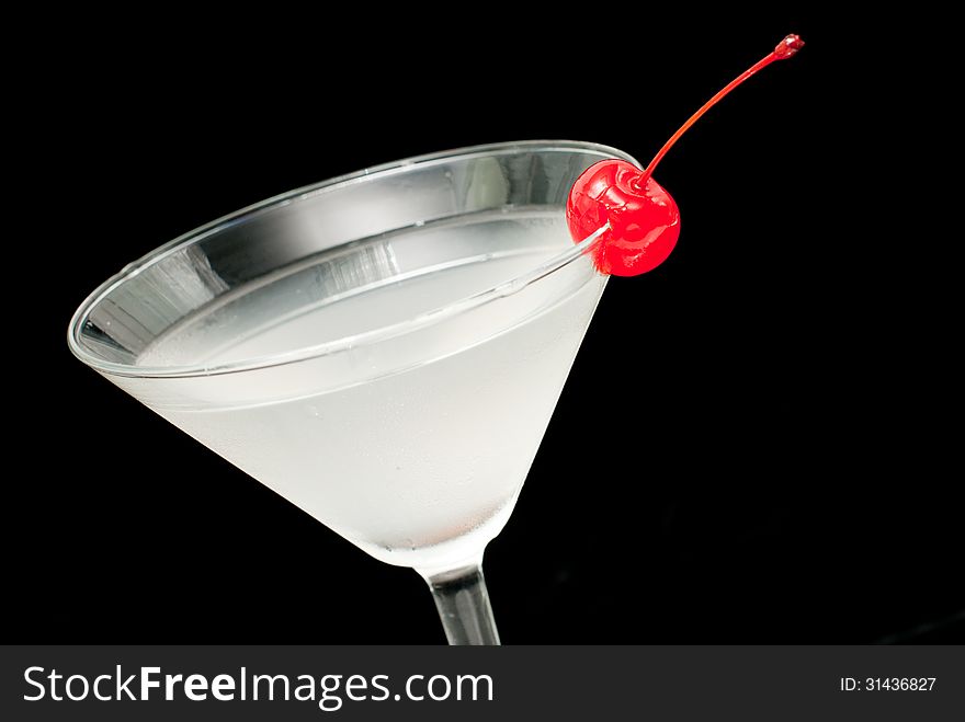 Cocktail in martini glass with red cherry closeup