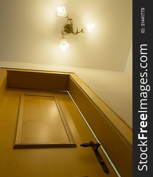 Fragment of classic home interior with wooden door and ceiling light. Fragment of classic home interior with wooden door and ceiling light