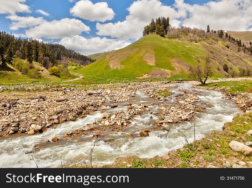 View to the foothills of the Caucasus mountains over stream near Arkhyz, Karachay-Cherkessia, Russia. View to the foothills of the Caucasus mountains over stream near Arkhyz, Karachay-Cherkessia, Russia