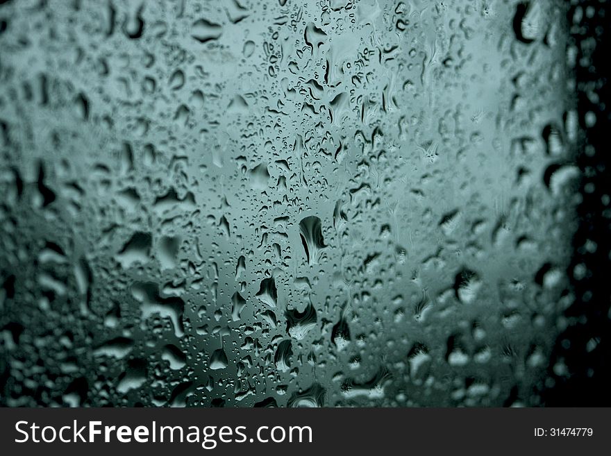 Wet drops of moisture on the glass dark background. Wet drops of moisture on the glass dark background