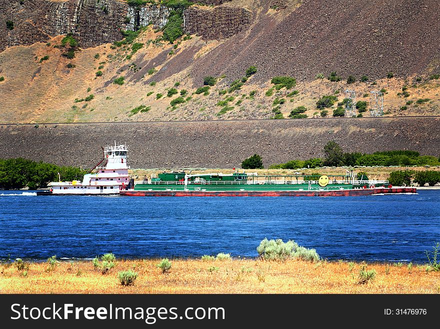 A tug boat pushing a barge in the traffic lane in the Columbia River Gorge. Common daily scene. A tug boat pushing a barge in the traffic lane in the Columbia River Gorge. Common daily scene.