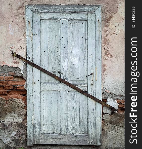 Old wooden door locked with a iron joist