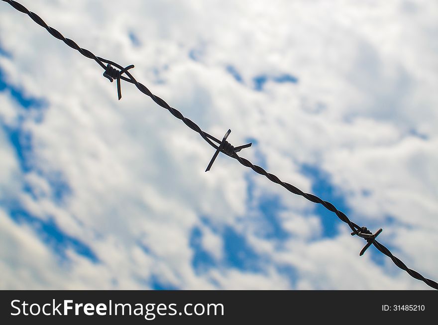 Barbed wires against cloudy sky