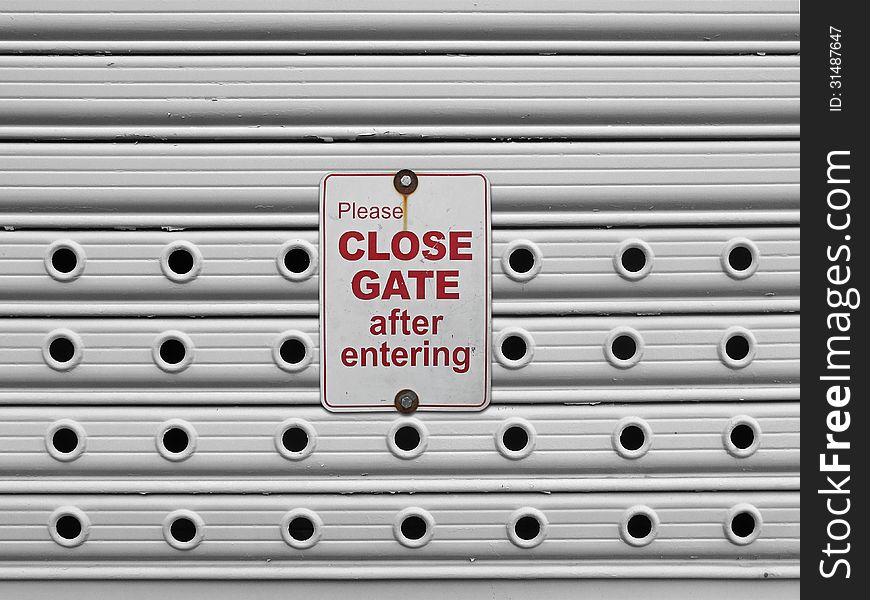 Please close sign on a light grey painted perforated roll up gates background. Please close sign on a light grey painted perforated roll up gates background