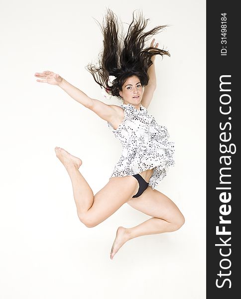 Portrait of a pretty young woman jumping in joy over white background, flying hair