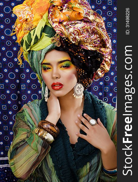 Black skinned bright woman with creative make up, many shawls on head like cubian woman