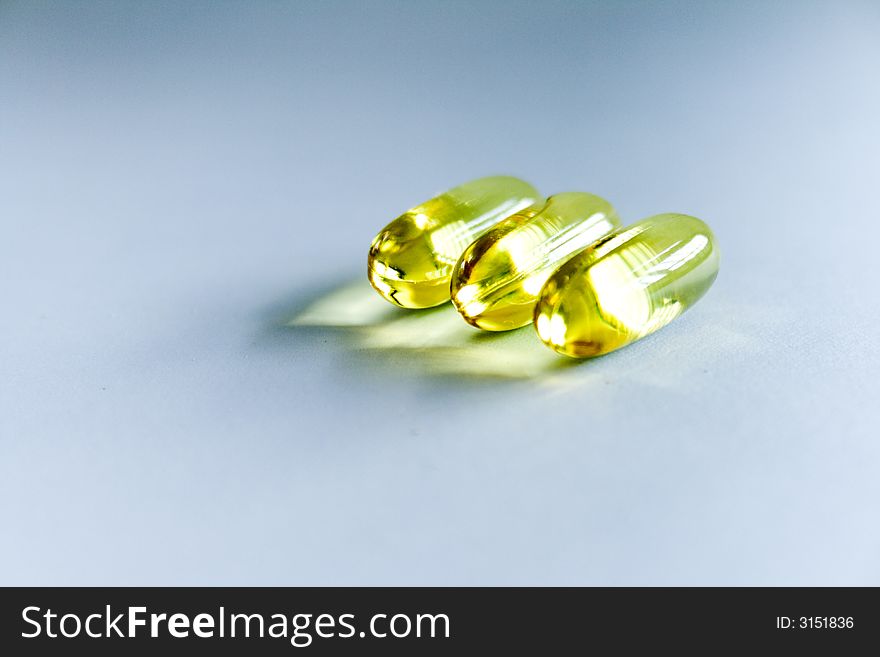 Three transparent yellow pills on white background