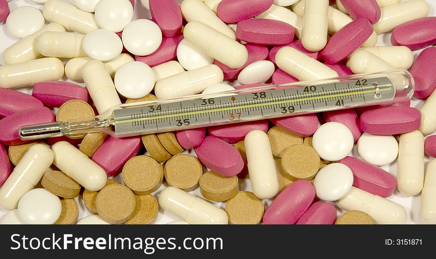 Red, white, brown pills and thermometer. Red, white, brown pills and thermometer