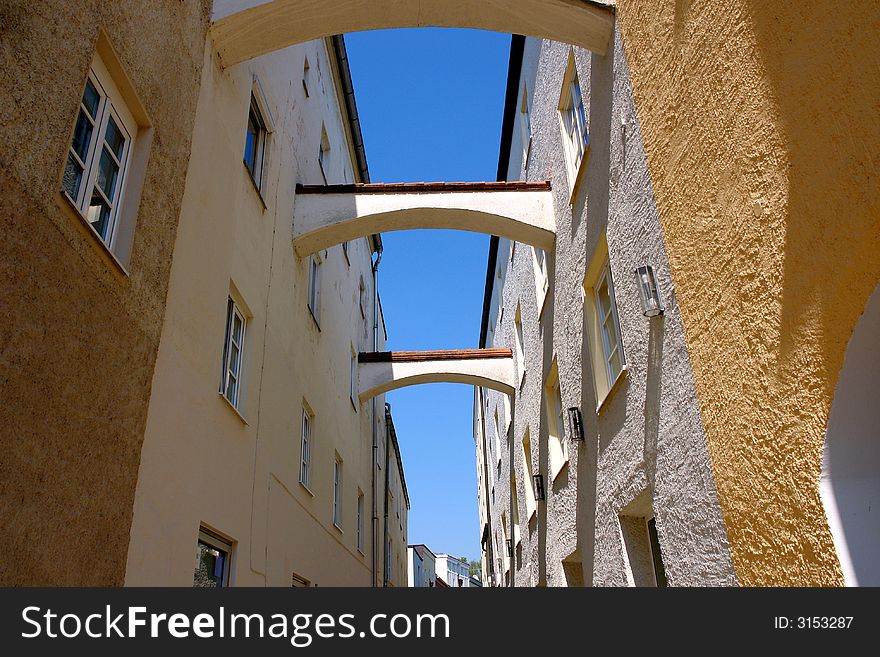 Old City narrow street. Small stone bridges between walls . Blue sky in the high . Bavaria , Muehldorf City,April 2007. Old City narrow street. Small stone bridges between walls . Blue sky in the high . Bavaria , Muehldorf City,April 2007.