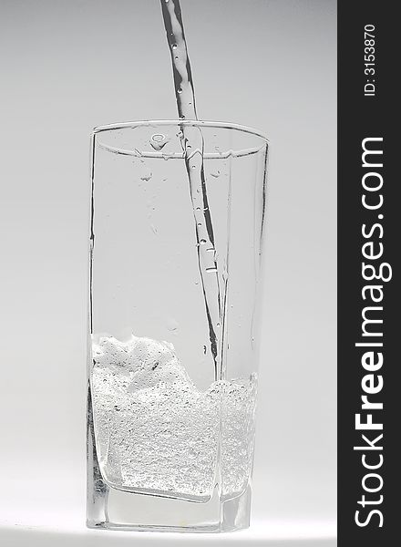 Jet of transparent water flowing in a glass and doing there water mixed with small bubbles. Jet of transparent water flowing in a glass and doing there water mixed with small bubbles