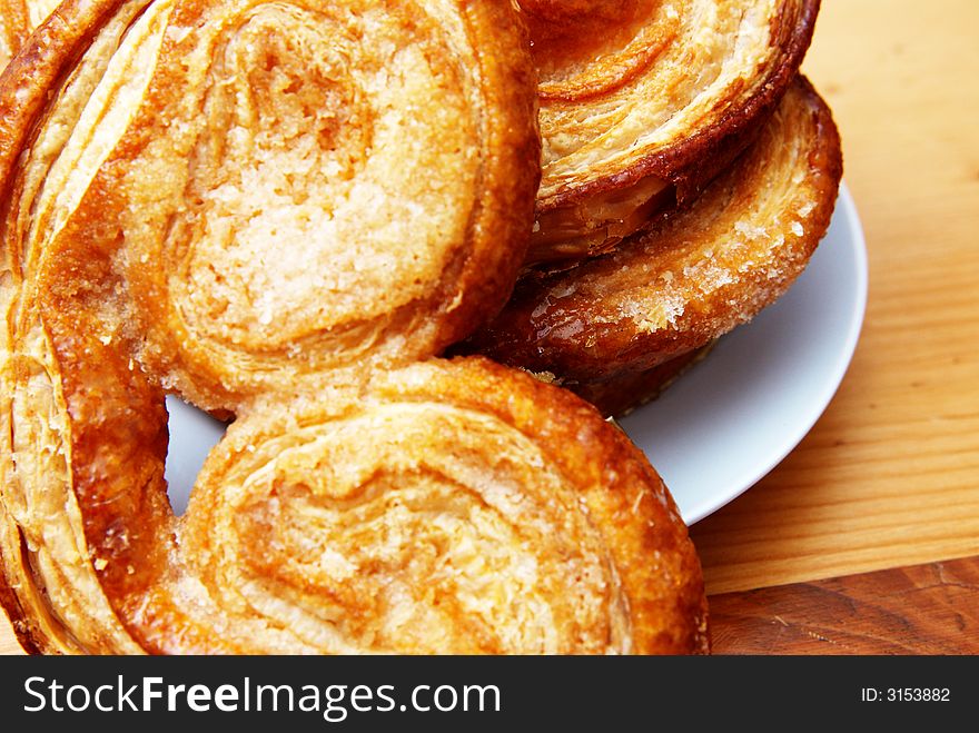 Palmier pastries on white saucer, shot on wooden board background