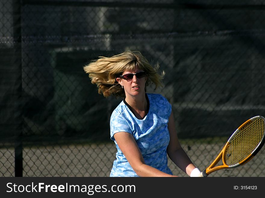 expressive face of female tennis player hitting the ball