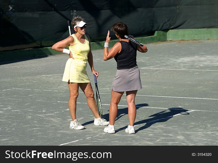 Two female tennis players having a disagreement on the court. Two female tennis players having a disagreement on the court