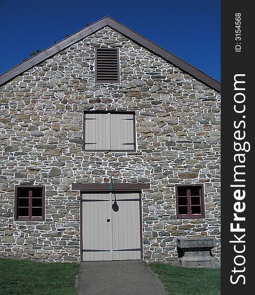Gray stone barn with bright blue sky. Color digital photo.