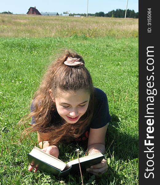 The young smile girl with book on the grass. The young smile girl with book on the grass