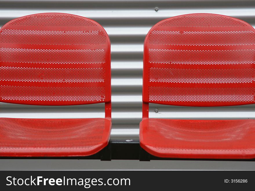 Close up of red chairs in front of a steel wall. Close up of red chairs in front of a steel wall