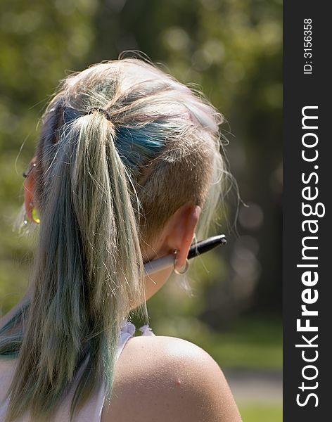 Young girl with colored hair and ornaments through her ears takes in the sun. Young girl with colored hair and ornaments through her ears takes in the sun.