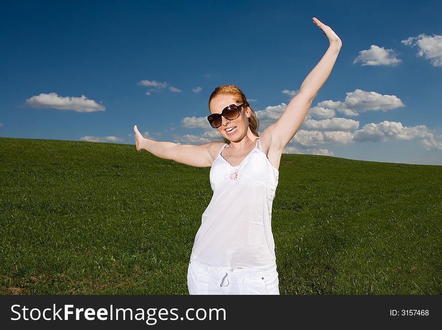 Woman on green meadow, happy and free. Grass going to the horizon, blue sky with clouds. Summery. Woman on green meadow, happy and free. Grass going to the horizon, blue sky with clouds. Summery