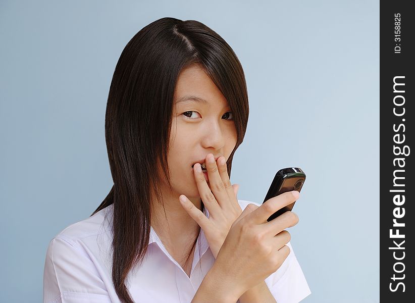 A young asian woman with a look of surprise after receiving a text message on her handphone. A young asian woman with a look of surprise after receiving a text message on her handphone