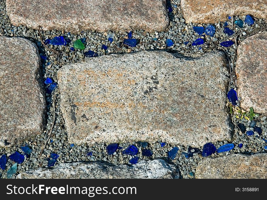 Pavement with blue and green pieces of broken glass