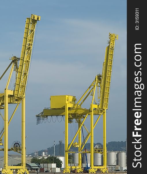 Two large, yellow container cranes at an industrial harbour. Two large, yellow container cranes at an industrial harbour.