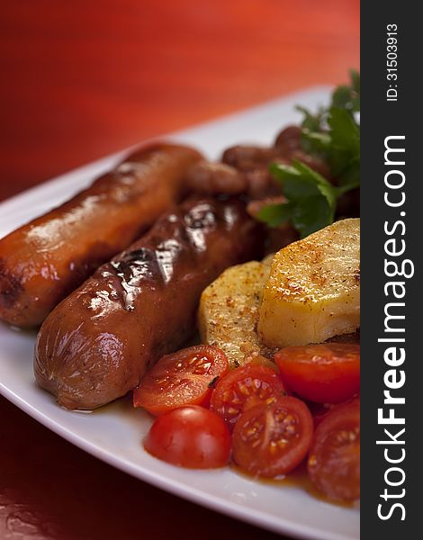 Sausage, potato and tomato on plate. Sausage, potato and tomato on plate