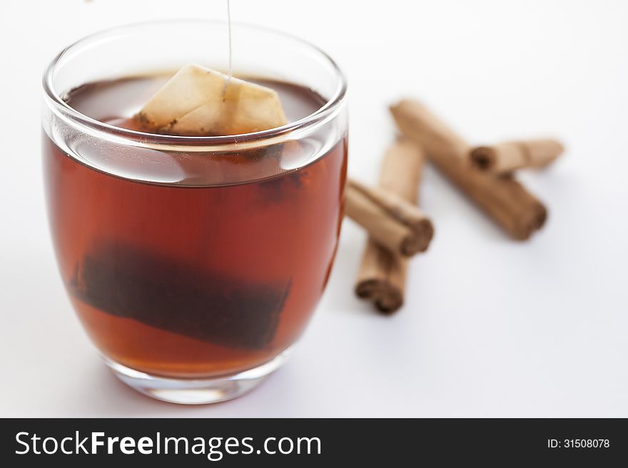 Cup of red tea with cinnamon on white background