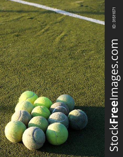 Group of tennis balls in front of white line on green grass on court. Group of tennis balls in front of white line on green grass on court