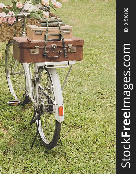 Vintage bicycle on the field with a basket of flowers and bag