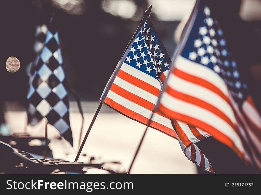 Small American flags and checkered flag flying against evening light