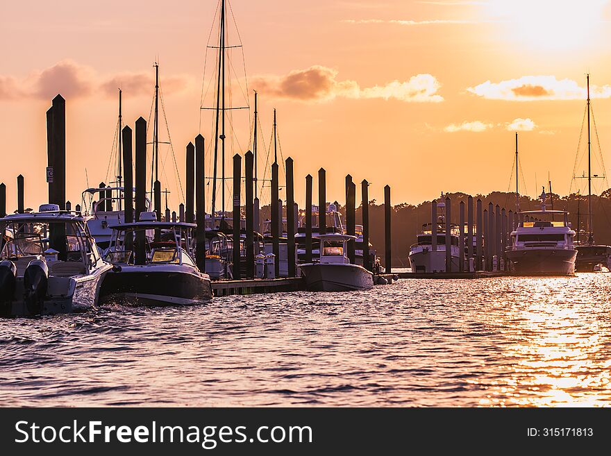 Group of boats docked at busy harbor at sunset