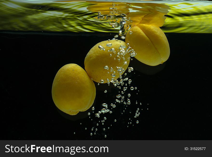 Apricots, fresh air in the water with bubbles on a black background. Apricots, fresh air in the water with bubbles on a black background