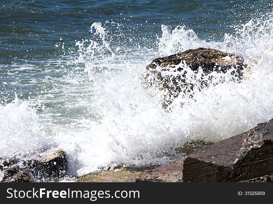 Waves breaking on a stony beach, forming a spray