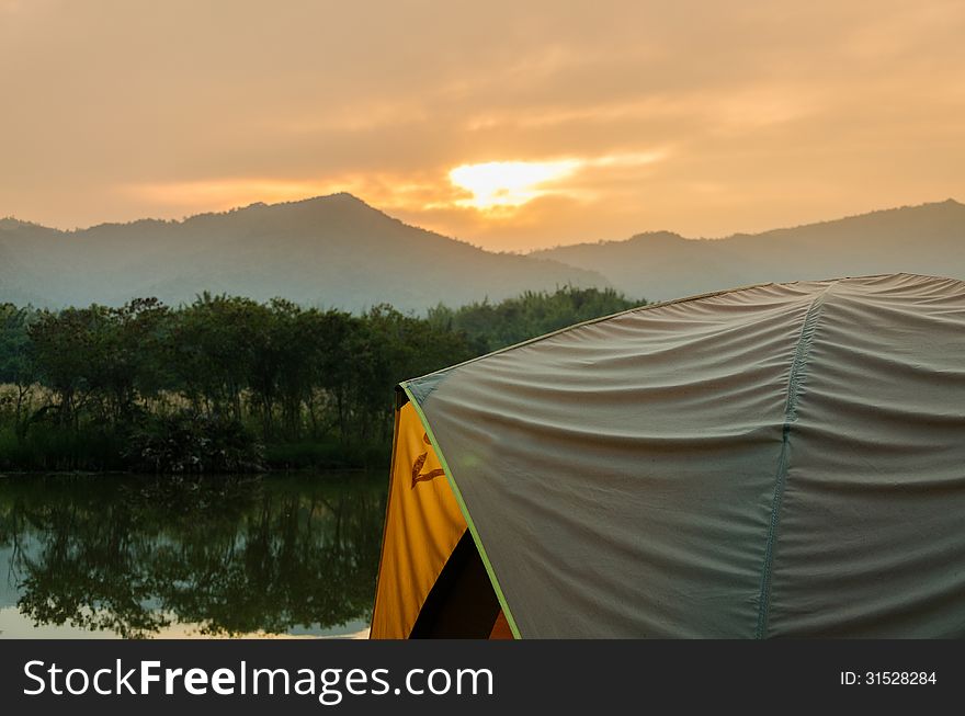 Tent set on the grassland of mountain in the sunrise