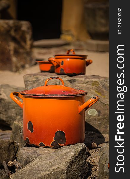 Two old orange pans with lids, together with a old orange bowl, drying in the sun ready for use. Two old orange pans with lids, together with a old orange bowl, drying in the sun ready for use.