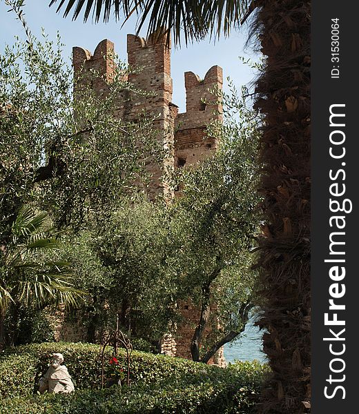 Old castle on Lake Garda with tree and hedge