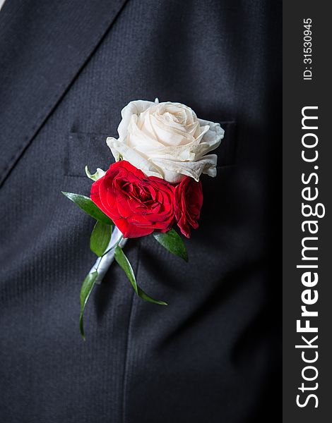 Wedding bouquet of roses on the lapel of his jacket