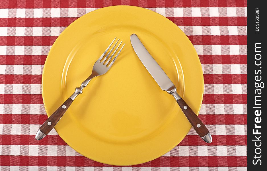 Cutlery and yellow plate on a tablecloth. Cutlery and yellow plate on a tablecloth.