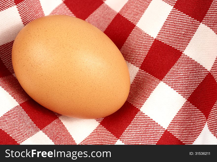Single brown egg on a tablecloth. Horizontal position.