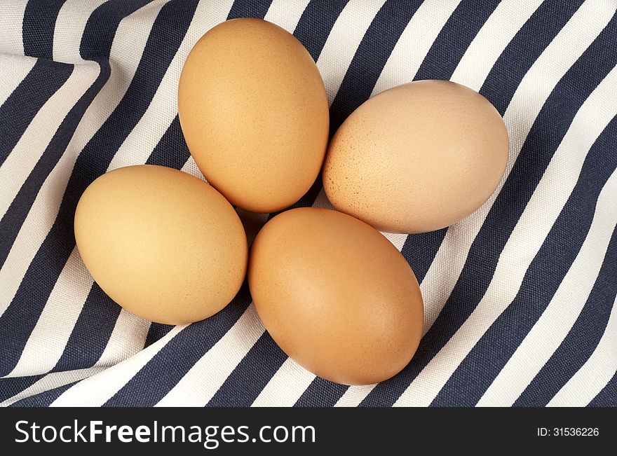 Four brown eggs on a tablecloth.