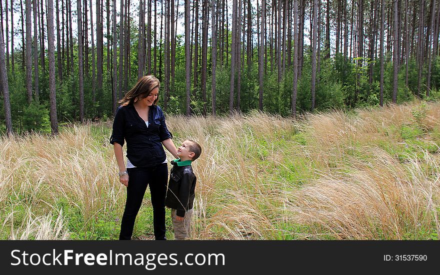 Pretty young mother looking down into smiling son s face while out in meadow