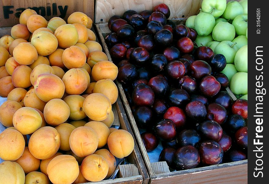 Assorted summer fruits displayed in wooden boxes
