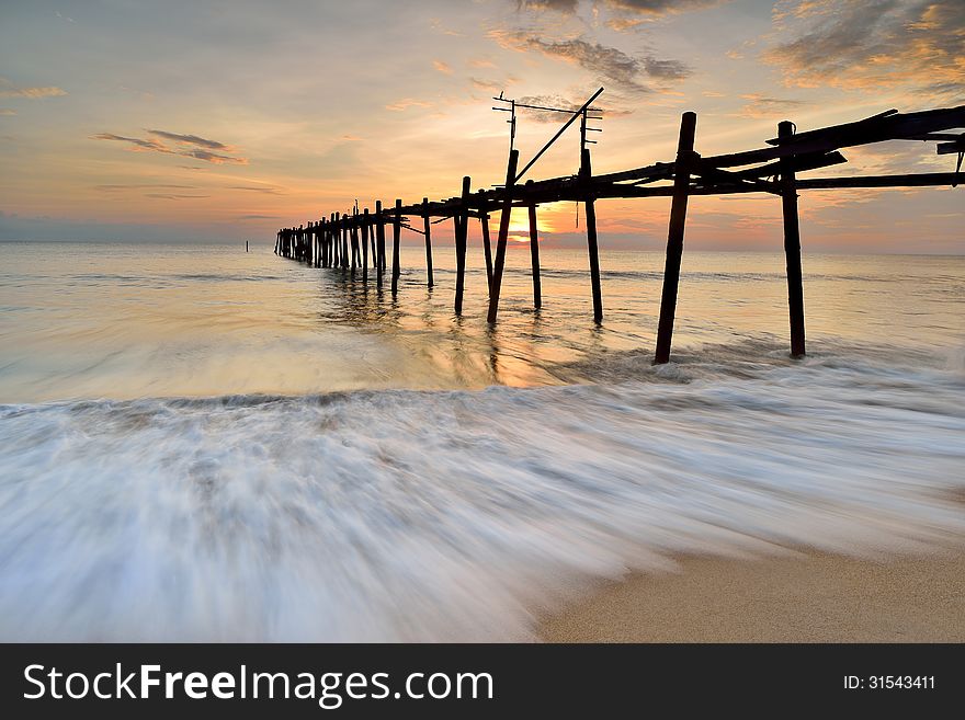 Old wooden bridge in the sea with sunset