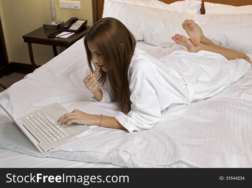 Portrait of beautiful brunette woman with laptop on bed at bedroom. Portrait of beautiful brunette woman with laptop on bed at bedroom