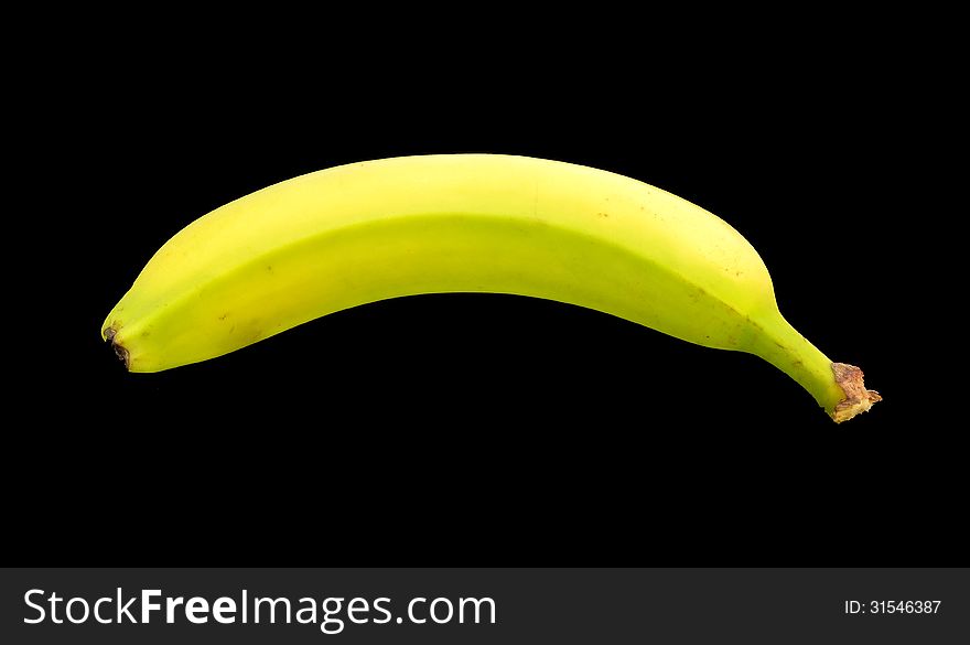A partially ripe banana on a black background.