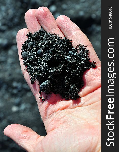 Black volcano sand from icelandic beach in the hand